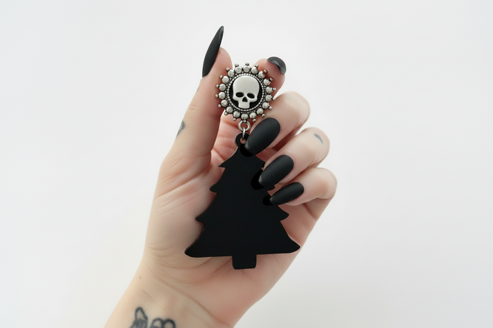 A pair of black dangle plug earrings with a Christmas tree design and a decorative skull and bones motif on top.